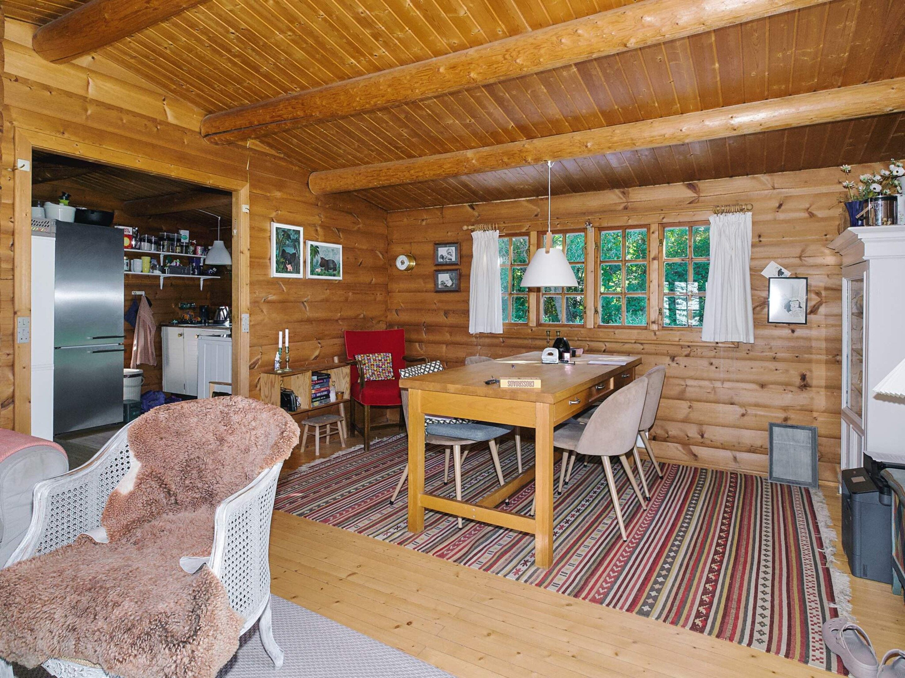 A log cabin interior with a dining area, kitchen, and a cozy living space.