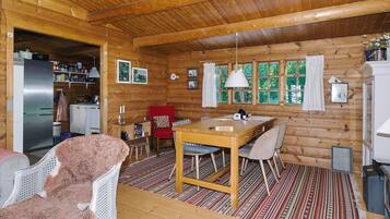 A log cabin interior with a dining area, kitchen, and a cozy living space.