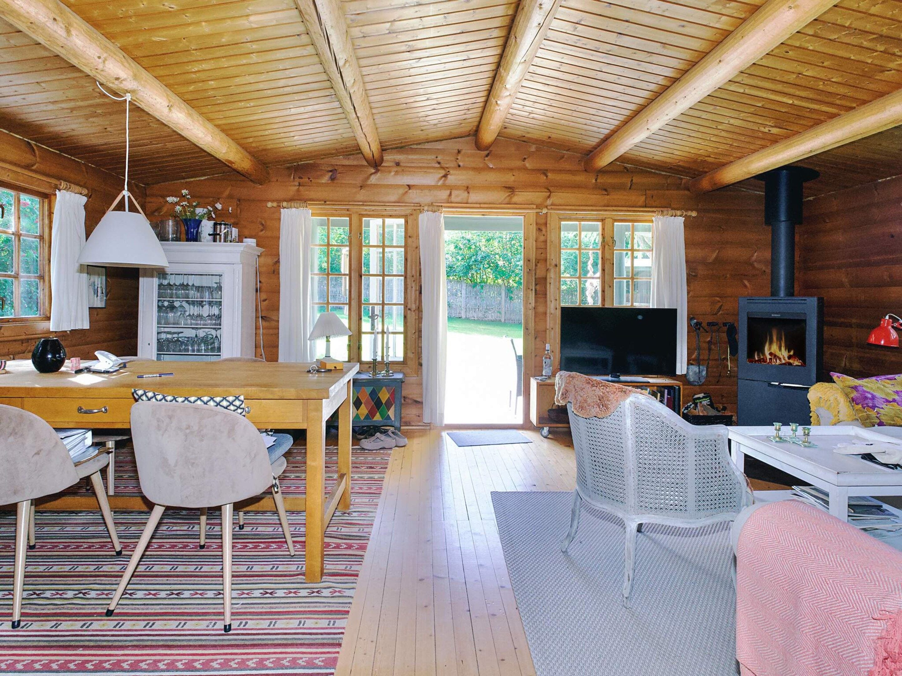 A wooden cabin interior with a dining area, a TV, and a fireplace.