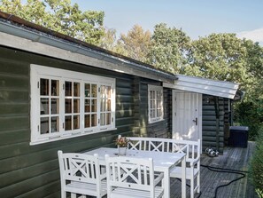 Eine Holzhütte mit einer Terrasse, einem Tisch mit Stühlen und einem Fenster mit Rollläden.