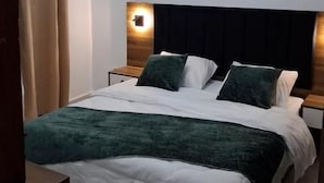 Un dormitorio con cama, mesitas de noche, cabecera y lámpara de techo.
