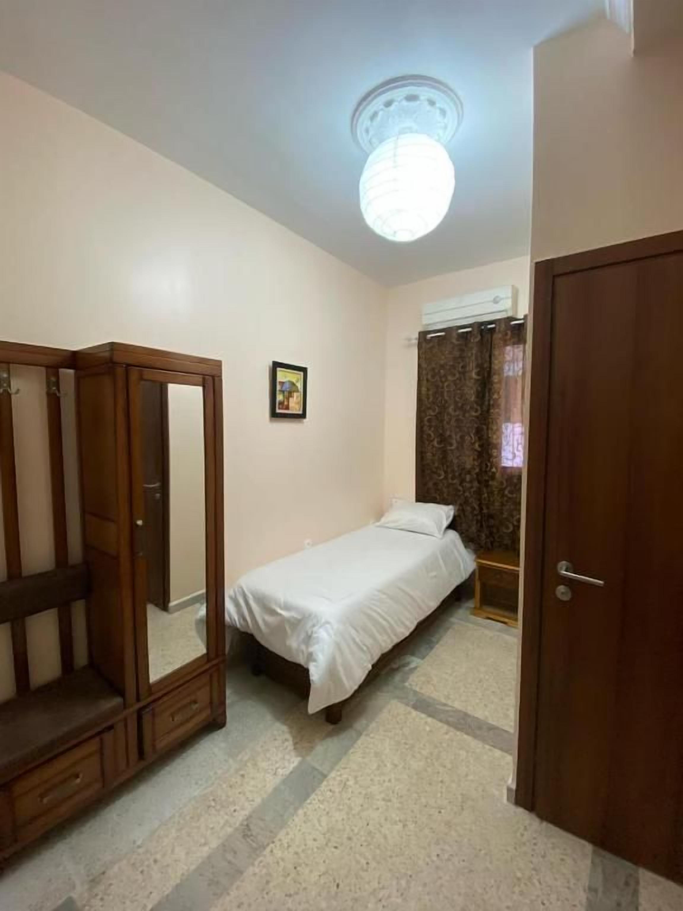Un dormitorio con una cama individual, un armario y una puerta.