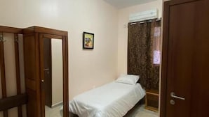 Un dormitorio con una cama individual, un armario y una puerta.