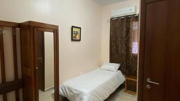 Un dormitorio con una cama individual, un armario y una puerta.