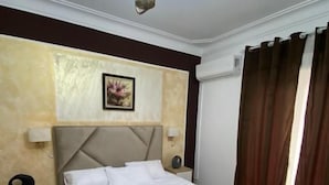 Una habitación de hotel con una cama grande, cabecera, lámparas de noche, alfombra y lámpara de techo.