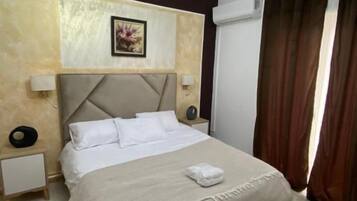 Una habitación de hotel con una cama grande, cabecera, lámparas de noche, alfombra y lámpara de techo.