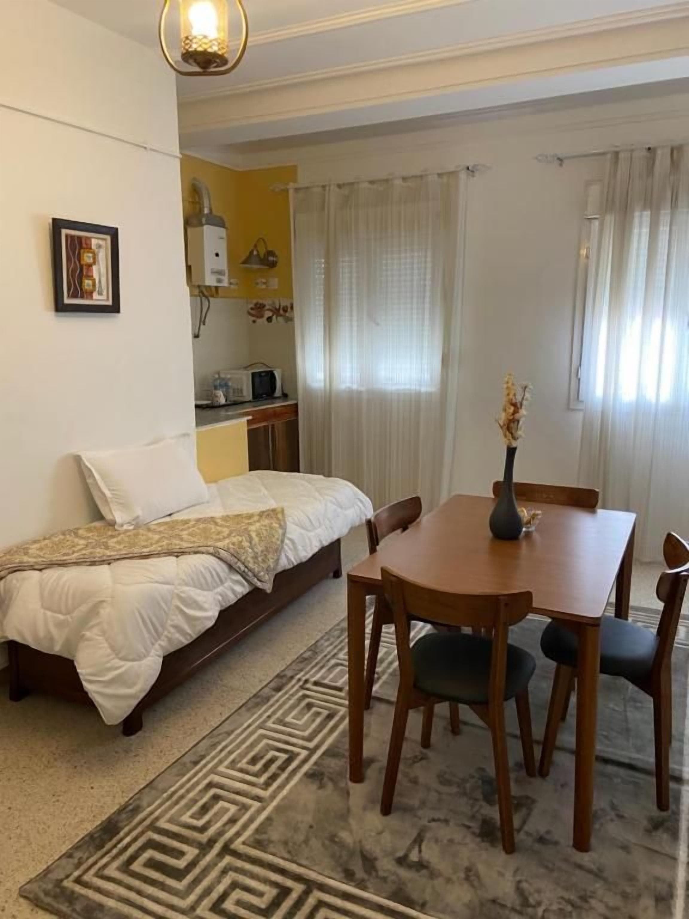 Una camera da letto con un letto, un comodino e un piccolo tavolo con sedie.