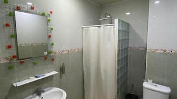 Un baño con lavamanos, inodoro, ducha y un espejo con azulejos decorativos.