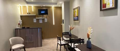 A reception area with a counter, chairs, tables, and a television.