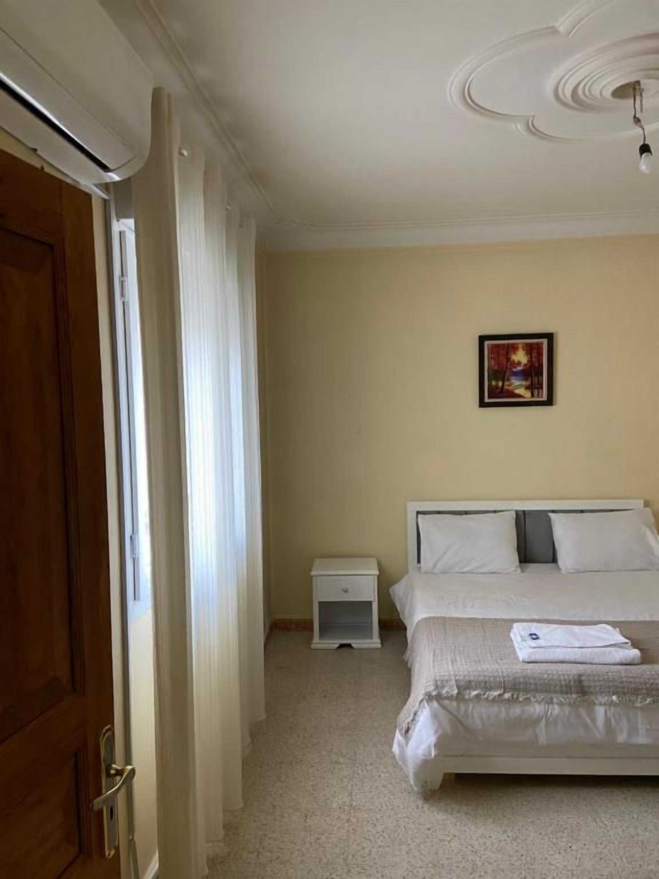 A bedroom with a bed, a nightstand, a door, and a ceiling fan.