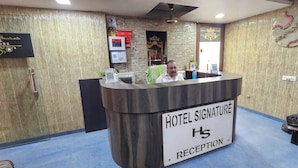 A hotel reception desk with a sign reading 'HOTEL SIGNATURE RECEPTION.' - Hotel Signature (Ahmedabad)