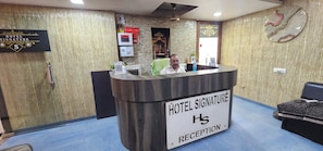 A hotel reception desk with a sign reading 'HOTEL SIGNATURE RECEPTION.' - Hotel Signature (Ahmedabad)