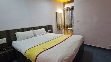 Una habitación de hotel con cama, mesita de noche, espejo y ventana con cortinas.