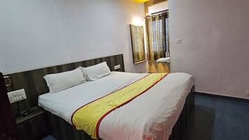 Une chambre d’hôtel avec un lit, une table de chevet, un miroir et une fenêtre avec des rideaux.