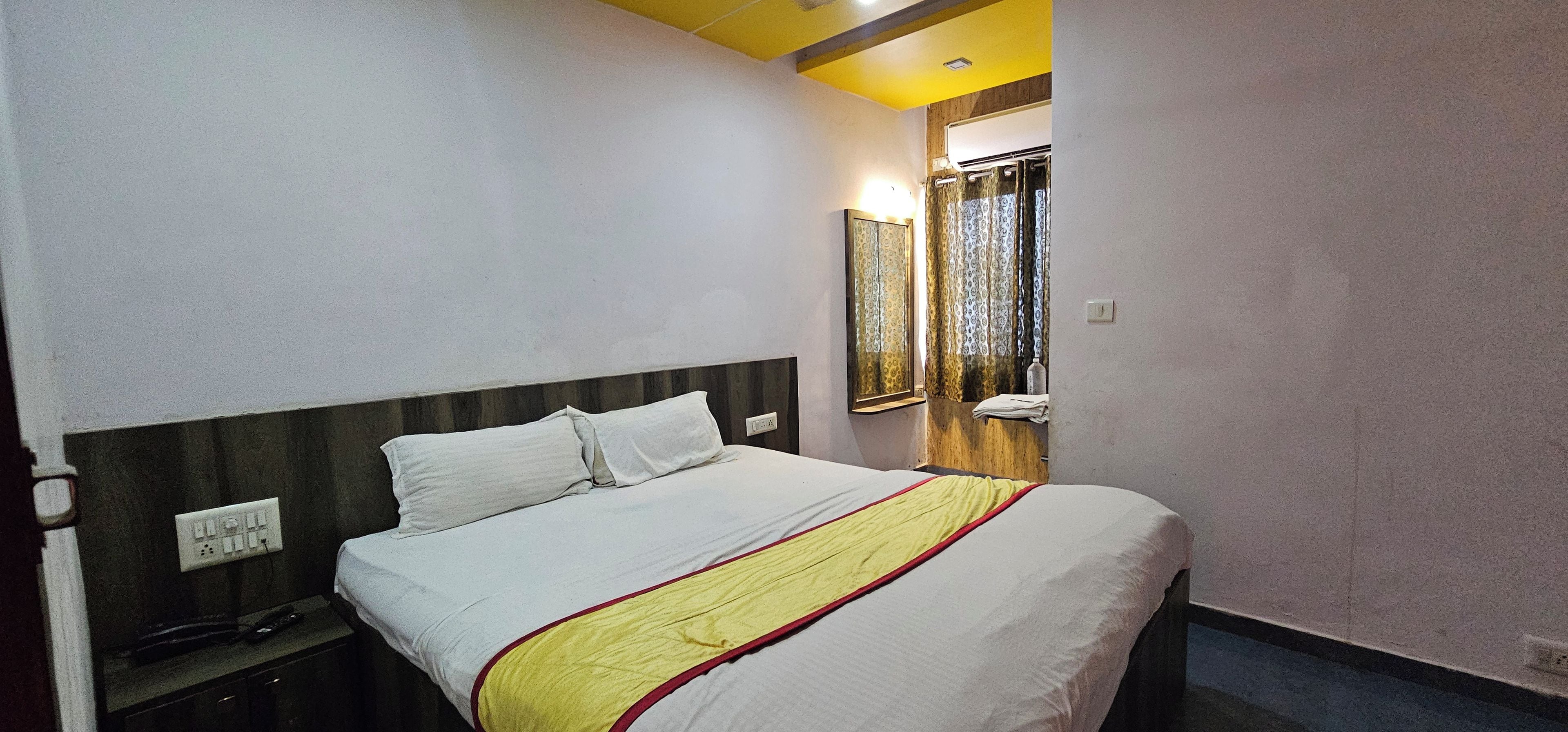 Una habitación de hotel con cama, mesita de noche y espejo.