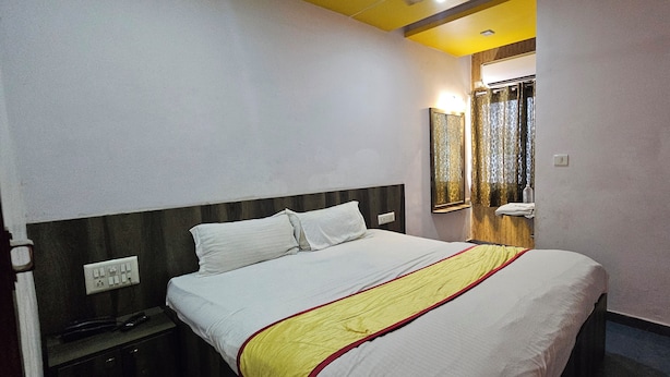 A hotel room with a bed, bedside table, and a mirror. - Hotel Signature (Ahmedabad)