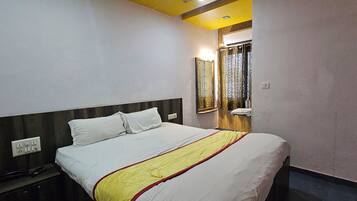 Una habitación de hotel con cama, mesita de noche y espejo.