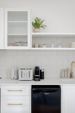 A kitchen with white cabinetry, a coffee maker, a toaster, and a dishwasher.