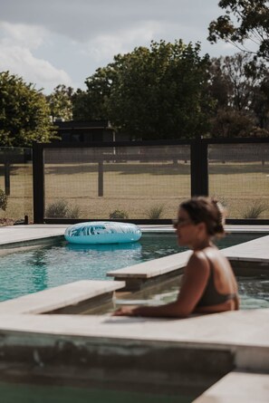 A swimming pool with a blue inflatable float and a person sitting on the edge.