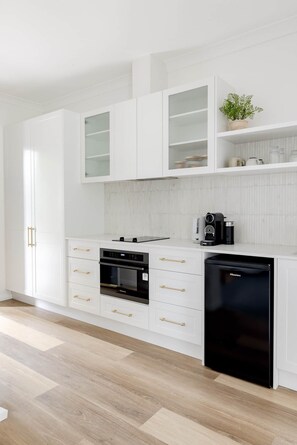 A modern kitchen with white cabinetry, a black dishwasher, and a coffee maker.