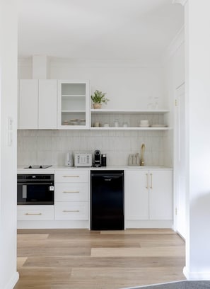 A modern kitchen with white cabinetry, a black dishwasher, and a countertop with a coffee maker and toaster. - The Wellness Farm Mindful Villa 5 (Broke)