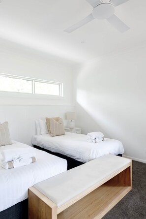 A modern hotel room with two single beds, a bench, a ceiling fan, and a window providing natural light. - The Wellness Farm Mindful Villa 5 (Broke)