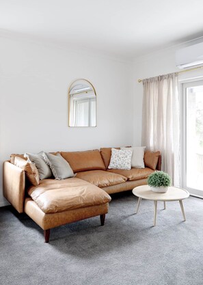 A living room with a brown leather sofa, a round coffee table, and a potted plant. - The Wellness Farm Peace Villa 2 (Broke)