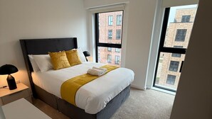 Una camera da letto con un letto, un comodino, una lampada e una finestra vista edifici.