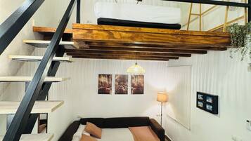 Un dormitorio estilo loft con una cama litera, una escalera de madera y un nivel entre piso.