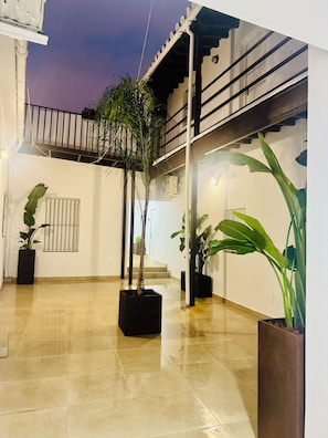 A spacious courtyard with tiled flooring, potted plants, a staircase, and a balcony with railings. - "Your Charming Retreat" Apartment with a Mezzanine in Alegría de Jerez (Jerez de la Frontera)