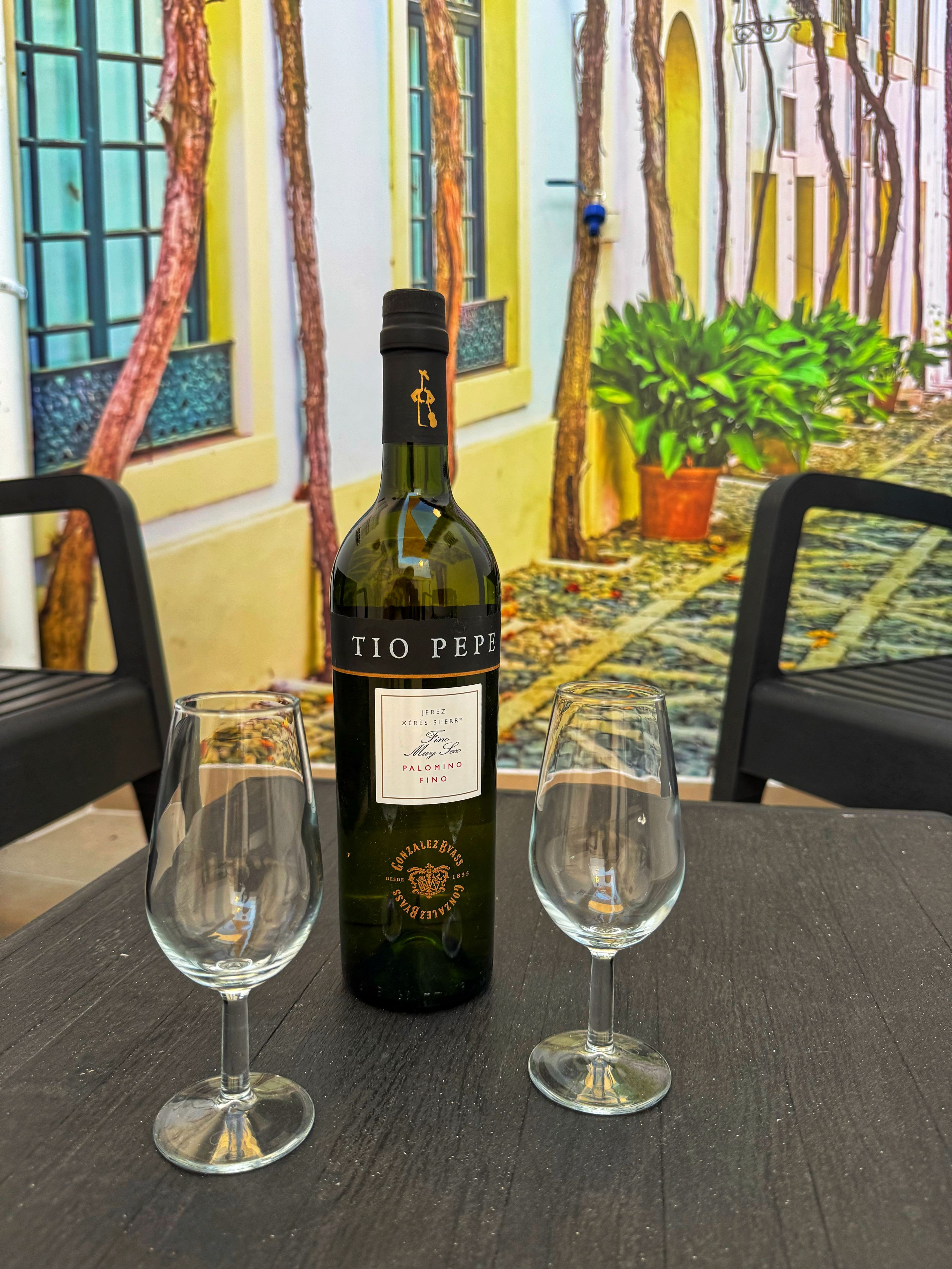 Una botella de vino Tio Pepe y dos copas de vino vacías sobre una mesa.