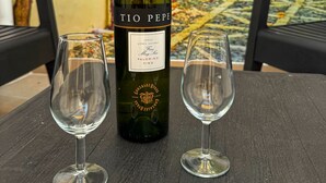 Eine Flasche Tio Pepe Wein und zwei leere Weingläser auf einem Tisch.