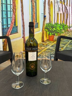 Una bottiglia di vino Tio Pepe e due bicchieri da vino vuoti su un tavolo.