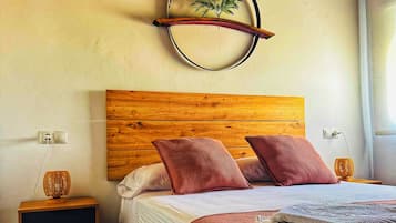 Una camera da letto con una testiera in legno, un letto con cuscini rossi, un comodino con una lampada e un decoro circolare a parete.