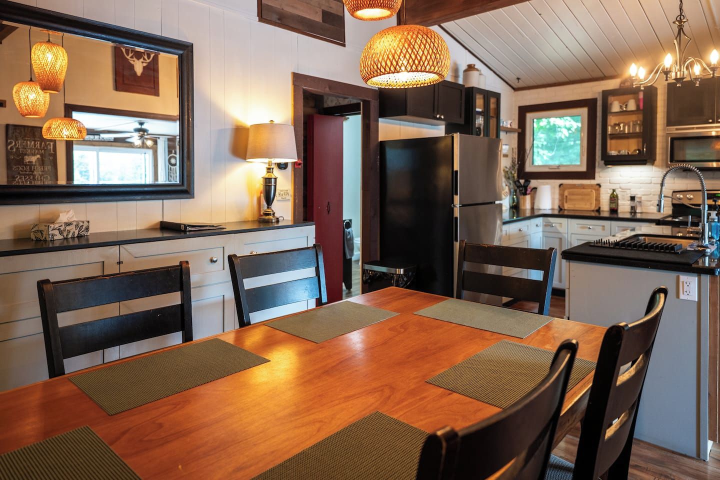 Cozinha moderna com mesa de jantar de madeira, cadeiras e iluminação pendente.