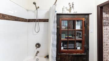 A bathroom with a shower, a wooden cabinet with glass doors, and a tiled wall.