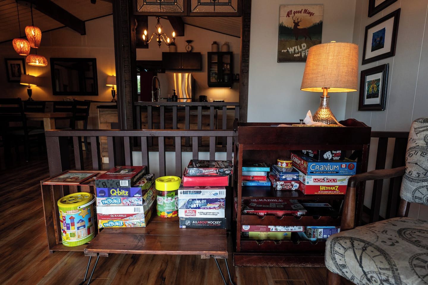 A living room with a wooden coffee table holding board games, a lamp, and framed pictures on the wall.