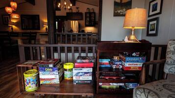 A living room with a wooden coffee table holding board games, a lamp, and framed pictures on the wall.