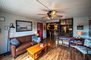 A cozy living room with a brown leather sofa, wooden coffee table, and a ceiling fan. - Fall Cliff Views | Water toys & Cozy Lakehouse (McKellar)