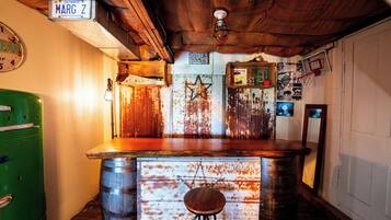 A rustic bar area with a wooden counter, a vintage green refrigerator, and a wall-mounted sign reading 'MARG Z'.