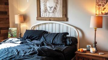 Ein Schlafzimmer mit einem Bett, zwei Nachttischlampen, einem Nachttisch mit einer Kerze und einem Bild an der Wand.