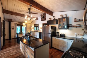 A modern kitchen with wooden beams, a central island, and a dining area with a view.