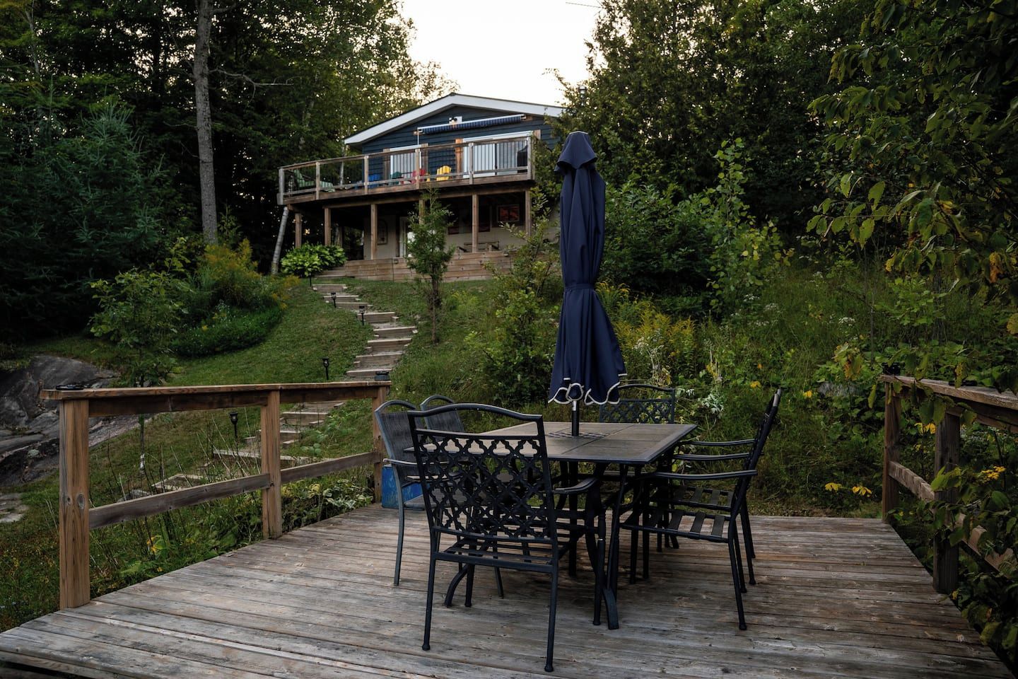 A wooden deck with a table and chairs, a covered area with a blue canopy, and a house in the background.