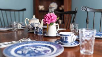 A dining table set with blue and white porcelain dinnerware, including plates, cups, and a teapot.