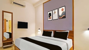 Ein Hotelzimmer mit einem Bett, einem Flachbildfernseher, einem Spiegel und Kunstwerken an der Wand.