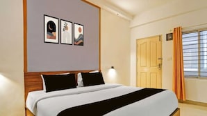 Ein Hotelzimmer mit einem Bett, einer Tür und einem mit Vorhängen versehenen Fenster.