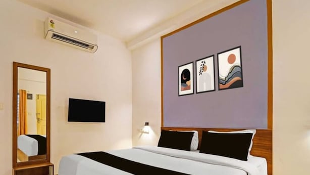 Ein Hotelzimmer mit Bett, Spiegel, Flachbildfernseher und Bildern an der Wand.