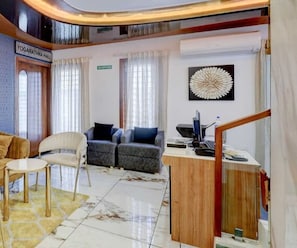 A hotel lobby with a reception desk, seating area with sofas and chairs, and a sign for the Yogarathna Hall.