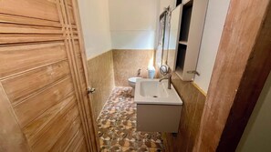 Une salle de bain avec une porte en bois, un lavabo, des toilettes et un miroir.