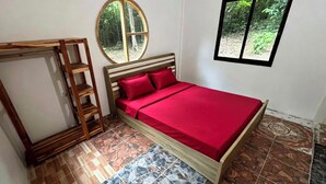 A bedroom with a bed, a wooden ladder, a round mirror, and a window with a view of greenery. - Kood Life !  1-bedroom   JUNGLE SUITE with AC in charming Ko Kut (ko kut)